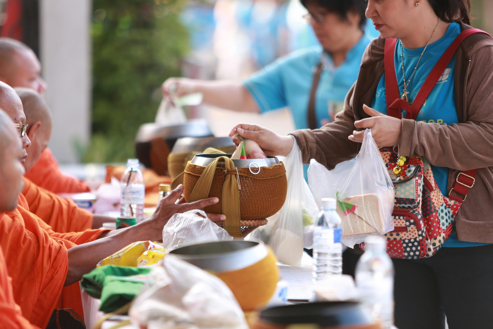 Woman handing food to Buddhist monks outside